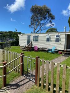a caravan parked in a yard with a fence at Caravan at Harbour House in Moelfre