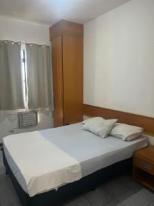 une chambre avec un grand lit blanc et une fenêtre dans l'établissement Conforto e Comodidade Jardim de Alah, à Campos dos Goytacazes