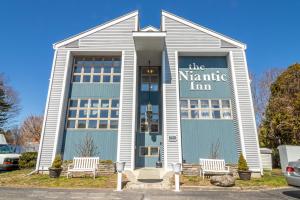 a white and blue building with two chairs in front at The Niantic Inn in Niantic