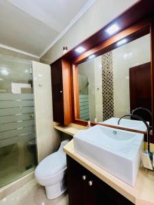 a bathroom with a sink and a toilet and a mirror at Machala departamento lujo cerca del hotel oro verde in Machala
