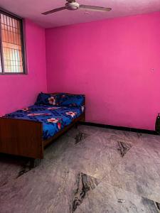 a bedroom with a pink wall and a bed at MK Residency Rooms in Tiruvannāmalai