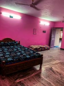 a room with a bed and a pink wall at MK Residency Rooms in Tiruvannāmalai