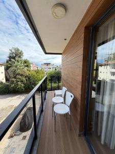 a balcony with two white chairs and a railing at Deluxe Beach Residence in Samsun