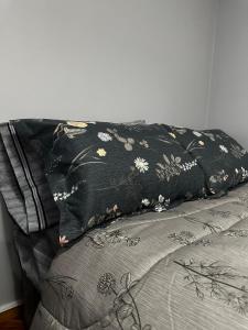 een zwart kussen met bloemen bovenop een bed bij Departamento Estudio, 4 personas Depto 2 in Temuco +2 foto's