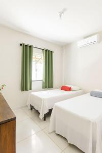 two beds in a room with green curtains at Casa Toniatti 2 in Barra Grande