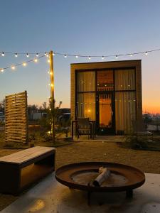 a backyard with a fire pit and a building with lights at Marina Strandbad TinyHouse Pawradise in Olburgen