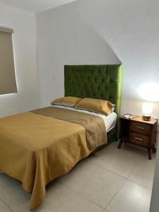 a bedroom with a bed with a green headboard and a table at Casa Mujer Ceiba - Indoor Pool - We Invoice in Tierra Colorada +32 photos
