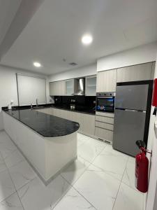 une grande cuisine blanche avec un comptoir noir dans l'établissement Moroj Al Zain - M49, à Salalah