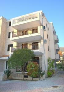 a large white building with a tree in front of it at Apartments Magic Time in Podstrana