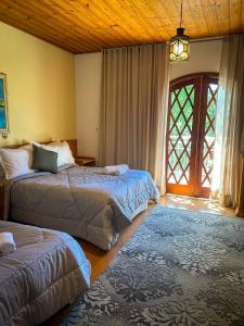 a bedroom with two beds and a large window at Pousada Doce Vida in Campos do Jordão