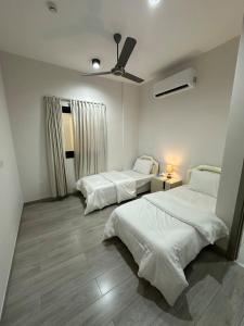 a bedroom with two beds and a ceiling fan at Moroj Al Zain - M77 in Salalah +13 photos