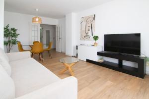 a living room with a white couch and a flat screen tv at Pacifico Beach Front in Málaga