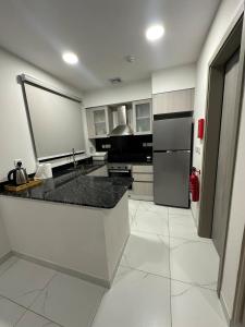 a kitchen with a black counter and a refrigerator at Moroj Al Zain - M57 in Salalah