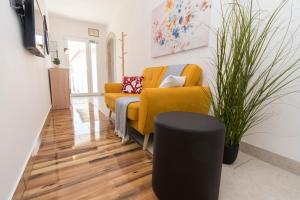 ein Wohnzimmer mit einem gelben Sofa und einem Stuhl in der Unterkunft Apartments Emmeline in Tisno