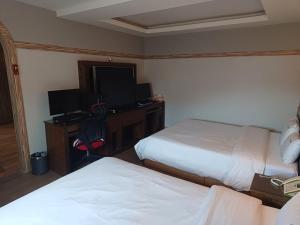 a hotel room with two beds and a desk with a television at Hotelharu in Eumseong