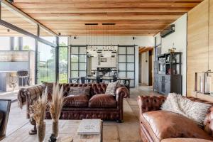 a living room with leather couches and a kitchen at Casa Viña Guesthouse in Tupungato