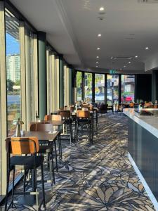 a dining room with tables and chairs and windows at Hotel Kingsley in Brisbane