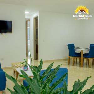 a living room with a table and chairs and a tv at Los Girasoles Apartamentos in Pueblo Bello