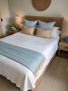 a large bed with blue and white sheets and pillows at Atlantic VIews Moullie Point in Cape Town