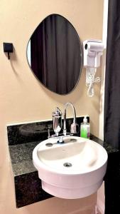 a bathroom with a white sink and a mirror at VA Apart Hotel Savassi in Divinópolis +46 photos