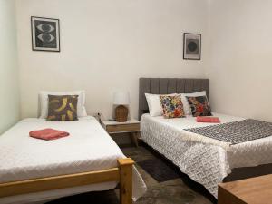 Un dormitorio con dos camas y una mesa con lámpara. en Casa Colibri - Hostel, en Pueblo Bello