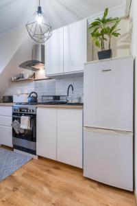 a kitchen with white cabinets and a refrigerator at Apartament Filipek in Szczawnica