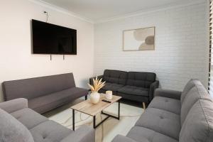 a living room with two couches and a tv at 3 Bedroom Deluxe Family Home in Rooty Hill