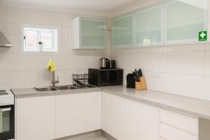 a white kitchen with a sink and a microwave at 3 Bedroom Deluxe Family Home in Rooty Hill