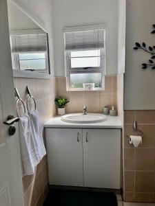 un bagno con lavandino bianco e due finestre di Luxurious Lagoon Retreat a Margate