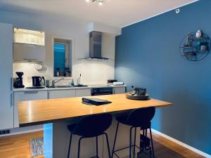 une cuisine avec des murs bleus et un comptoir en bois avec des tabourets dans l'établissement Bergen Centrum Modern Apartment, à Bergen