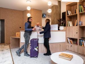 a man and a woman standing at a counter at Mercure Grenoble Centre Alpotel in Grenoble