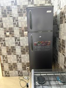 a black refrigerator in a kitchen with a stove at Résidence Hoteliere Marie Mbaye in Saly Portudal