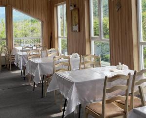une salle à manger avec des tables et des chaises blanches et des fenêtres dans l'établissement Densaulyq Resort & Wellness - Almaty Region, à Taūtürgen