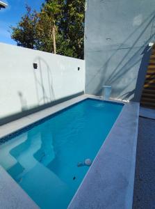 a swimming pool in a backyard with a white wall at Hostel de Niko Bombinhas in Bombinhas