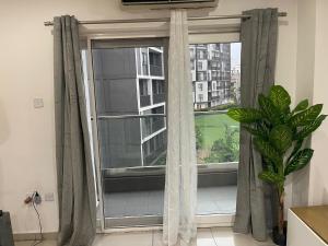 une fenêtre avec des rideaux dans une pièce avec une plante dans l'établissement Kings Luxury 1 bedroom at Gallery, à Accra