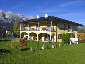 a large yellow house with a large yard with mountains at Villa Castelli in Schladming