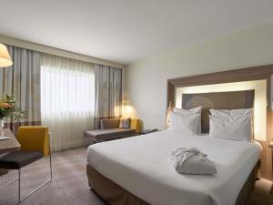 une chambre d'hôtel avec un grand lit blanc et des chaises dans l'établissement Novotel Paris La Defense Esplanade, à Courbevoie