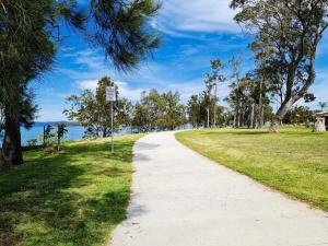 a walking path in a park with trees and the ocean at Tranquility by the Lake in Karraganbah