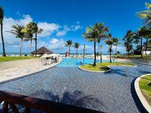 einen Pool am Strand mit Palmen in der Unterkunft Lindo 2Qts Beira Mar - Beach Classe Muro Alto 6207 - Porto de Galinhas - By Anfitrião Legal in Porto De Galinhas
