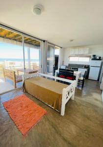 a bedroom with a bed and a living room with a kitchen at Acacias PDD in Punta Del Diablo