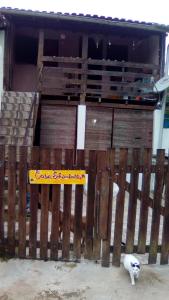 a white cat standing next to a wooden fence at Camburi Casa Shamballa in São Sebastião