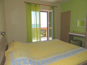 a bedroom with a bed and a window with a balcony at Apartments Denona in Novalja