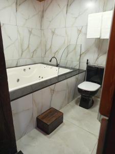 a bathroom with a bath tub and a toilet at Pousada Canto do Sossêgo in Brumadinho