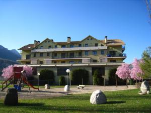 un grand bâtiment avec une aire de jeux dans un parc dans l'établissement Apartamentos Naspún, à Campo