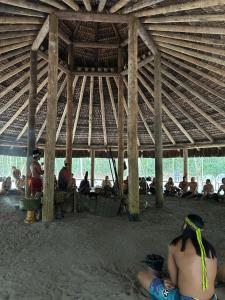a group of people sitting on the beach under a hut at Chalé Vila Jasmim Caraíva bahia in Caraíva
