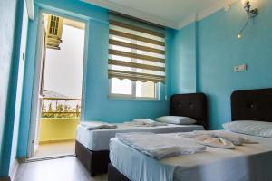 twee bedden in een kamer met blauwe muren en een raam bij Misa Pension Apart in Guzelcamlı