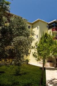 een appartementencomplex met een boom ervoor bij Misa Pension Apart in Guzelcamlı