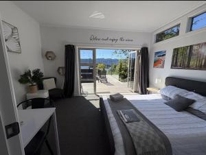 a bedroom with a bed and a view of a patio at Stylish Lake Ōkāreka Retreat Views, Spa in Rotorua in Rotorua