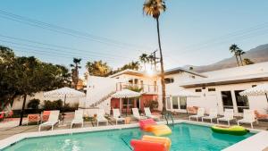 a pool with chairs and umbrellas in front of a house at 3 Private 1 Bedroom Units at The Wesley Sleeps 12 in Palm Springs