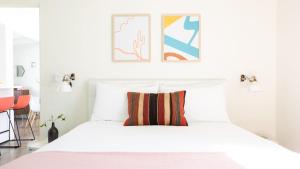 a bedroom with a white bed with a colorful pillow at 3 Private Rooms At The Wesley Hotel Perfect for Group Stays in Palm Springs +14 photos